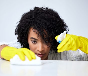 Shot of a young woman spraying down a counter to clean it.